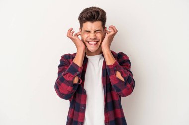 Beyaz arka planda izole edilmiş genç beyaz bir adam kulaklarını elleriyle kapatıyor..