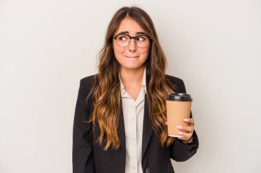 Young caucasian business woman holding a takeaway coffee isolated on white background confused, feels doubtful and unsure.