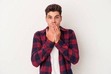 Beyaz arka planda izole edilmiş genç beyaz adam şok olmuş, ağzı ellerle kaplanmış, yeni bir şey keşfetmeye hevesli..