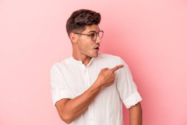 Kafkasyalı genç adam pembe arka planda izole edilmiş, başparmak uzakta, gülüyor ve kaygısız..