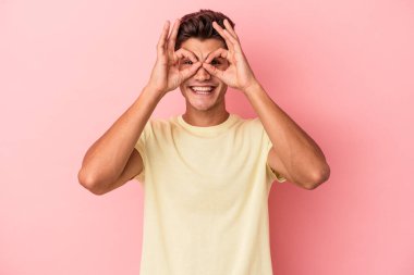 Pembe arka planda izole edilmiş genç beyaz adam gözlerinde sorun olmadığını gösteriyor.