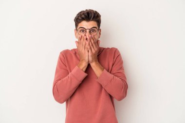 Beyaz arka planda izole edilmiş genç beyaz adam şok olmuş, ağzı ellerle kaplanmış, yeni bir şey keşfetmeye hevesli..