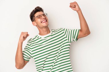 Beyaz arka planda izole genç beyaz adam özel bir günü kutluyor, atlıyor ve enerjiyle kollarını kaldırıyor..