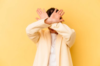 Arjantinli genç kadın sarı arka planda izole edilmiş iki kolu çapraz tutuyor, inkar kavramı.