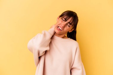 Arjantinli genç bir kadın sarı arka planda izole edilmiş, sabit yaşam tarzından dolayı boyun ağrısı çekiyor..