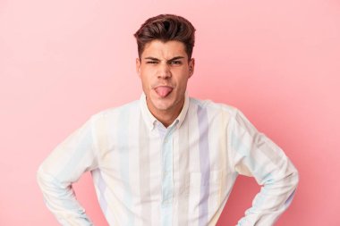 Genç, beyaz bir adam pembe arka planda izole edilmiş komik ve dost canlısı bir dil kullanıyor..