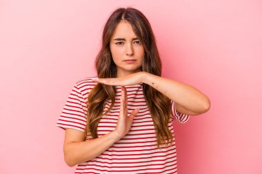 Pembe arka planda izole edilmiş genç beyaz kadın bir mola hareketi gösteriyor..