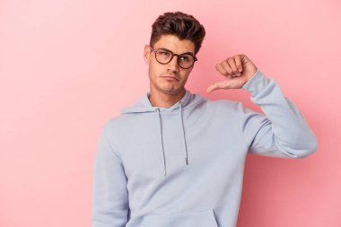 Pembe arka planda izole edilmiş genç beyaz bir adam hoş olmayan bir jest yapıyor. Anlaşmazlık konsepti.