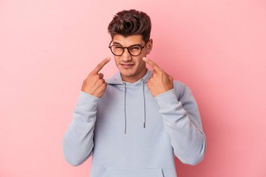 Kafkasyalı genç bir adam pembe arka planda izole edilmiş ağlıyordu, bir şeyden mutsuzdu, acı ve kafa karışıklığı içeriyordu..