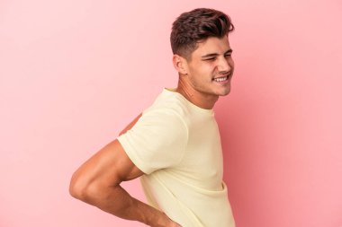 Pembe arka planda izole edilmiş beyaz bir adam sırt ağrısı çekiyor..