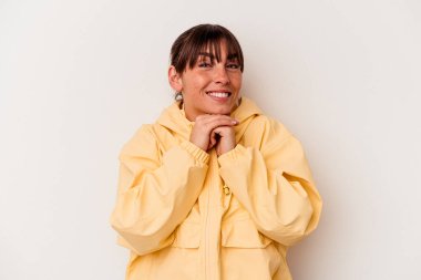 Beyaz arka planda izole edilmiş genç Arjantinli kadın ellerini çenesinin altında tutuyor, mutlu bir şekilde yana bakıyor..