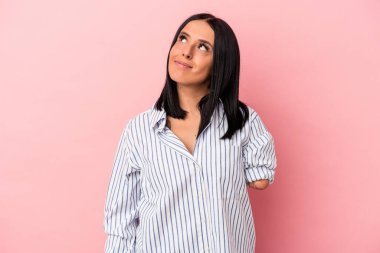 Tek kollu beyaz bir kadın pembe arka planda izole edilmiş hedeflerine ve amaçlarına ulaşma hayali kuruyor.