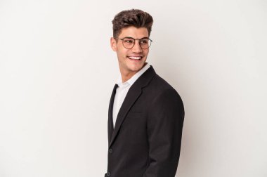 Beyaz arka planda soyutlanmış genç beyaz bir adam gülümsüyor, neşeli ve keyifli görünüyor..