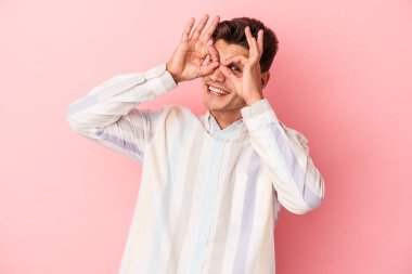 Pembe arka planda izole edilmiş genç beyaz adam gözlerinde sorun olmadığını gösteriyor.