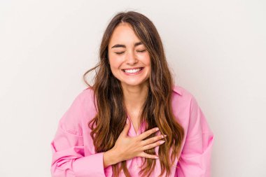 Beyaz arka planda izole genç beyaz kadın yüksek sesle gülüyor elini göğsüne koyuyor..