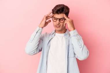 Kafkasyalı genç bir adam pembe arka planda izole edilmiş, başı ağrıyor, yüzüne dokunuyor..