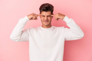 Pembe arka planda izole edilmiş genç beyaz adam bir göreve odaklanmış, parmaklarını işaret ediyor..