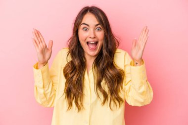 Pembe arka planda izole edilmiş genç beyaz kadın hoş bir sürpriz alıyor, heyecanlı ve el kaldırıyor..