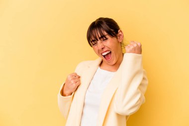 Arjantinli genç bir kadın sarı arka planda izole edilmiş tasasız ve heyecanlı bir şekilde tezahürat yapıyor. Zafer konsepti.