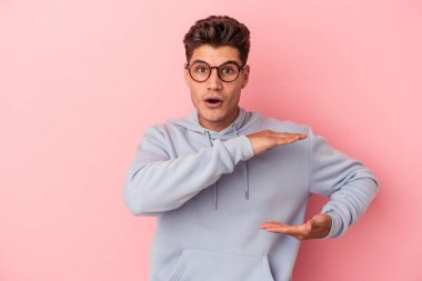 Pembe arka planda izole edilmiş beyaz bir adam iki eliyle bir şey tutuyor, ürün sunumu..