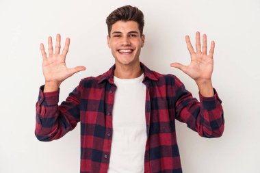Beyaz arka planda izole edilmiş beyaz tenli genç adam on numarayı elleriyle gösteriyor..