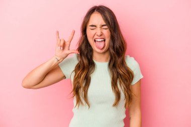 Pembe arka planda izole edilmiş genç beyaz kadın parmaklarıyla taş hareketi gösteriyor.