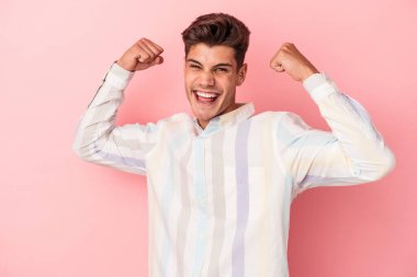Pembe arka planda soyutlanmış, tasasız ve heyecanlı genç bir beyaz adam. Zafer konsepti.