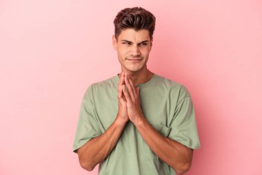 Kafkasyalı genç bir adam pembe arka planda izole edilmiş bir plan yapıyor, bir fikir kuruyor..