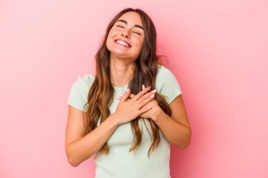 Pembe arka planda soyutlanmış beyaz bir kadın gülüyor, elini yüreğine koyuyor, mutluluk kavramını koruyor..