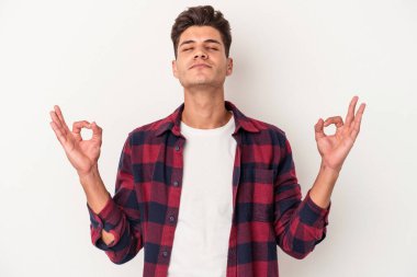 Beyaz arka planda izole edilmiş genç beyaz adam yoğun bir günün ardından rahatlıyor. Yoga yapıyor..