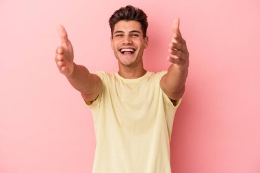 Pembe arka planda izole edilmiş genç beyaz adam kameraya sarıldığı için kendinden emin hissediyor..