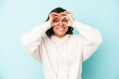 Mavi arka planda izole edilmiş genç latin kadın gözlerde sorun olmadığını gösteriyor.