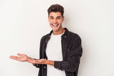 Beyaz arka planda izole edilmiş beyaz tenli genç bir adam palmiyesinde bir kopya alanı tutuyor..