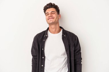 Beyaz arka planda izole edilmiş genç beyaz adam gülüyor ve gözlerini kapıyor, rahatlamış ve mutlu hissediyor..
