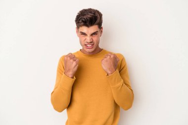 Beyaz arka planda izole edilmiş genç beyaz bir adam yumruğunu kameraya gösteriyor, agresif bir yüz ifadesi..