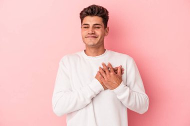 Pembe arka planda izole edilmiş genç beyaz bir adam, dostane bir ifadeye sahip, avuçlarını göğsüne bastırıyor. Aşk konsepti.