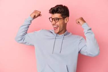 Pembe arka planda izole edilmiş genç beyaz adam zaferden sonra yumruğunu kaldırıyor, kazanan konsept..