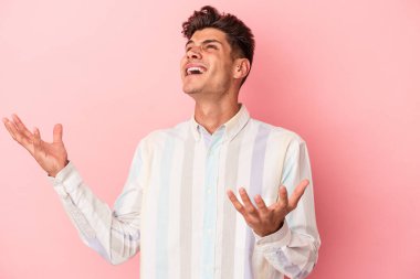 Pembe arka planda izole edilmiş genç beyaz adam gökyüzüne haykırıyor, yukarı bakıyor, hayal kırıklığına uğramış..