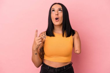 Tek kolu pembe arka planda izole edilmiş beyaz bir kadın ağzı açık bir şekilde üst tarafı işaret ediyor..
