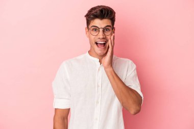 Pembe arka planda izole edilmiş genç beyaz adam yüksek sesle bağırıyor, gözleri açık ve elleri gergin tutuyor..