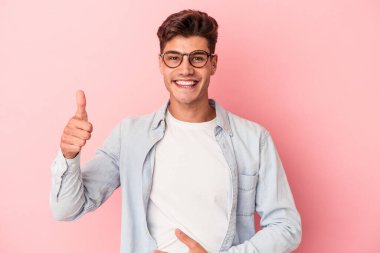 Pembe arka planda izole edilmiş genç beyaz adam karnına dokunuyor, nazikçe gülümsüyor, yemek yiyor ve tatmin oluyor..