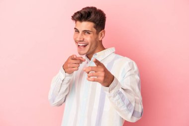 Pembe arka planda izole edilmiş genç beyaz adam. Önü işaret eden neşeli gülümsemeler..