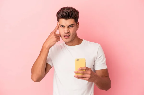 Młody Biały Mężczyzna Trzymając Telefon Komórkowy Odizolowany Różowym Tle Wykazując — Zdjęcie stockowe