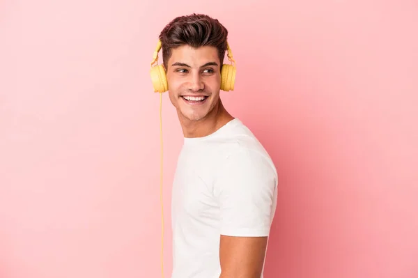 Young Caucasian Man Listening Music Isolated Pink Background Looks Aside — Stock Photo, Image