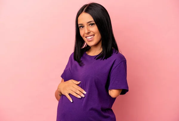 Young pregnant woman with one arm isolated on pink background