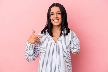 Pembe arka planda tek kollu beyaz bir kadın tişört fotokopisini elle gösteriyor, gururlu ve kendinden emin.