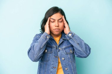 Mavi arka planda izole edilmiş genç Latin kadın şakaklara dokunuyor ve baş ağrısı çekiyor..
