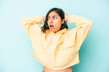 Genç Latin bir kadın mavi arka planda izole edilmiş bağırıyor, çok heyecanlı, tutkulu, bir şeyden memnun..