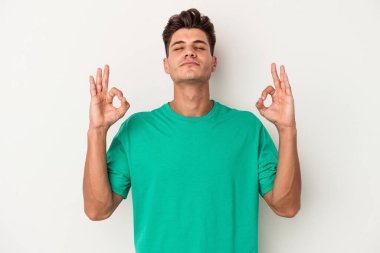 Beyaz arka planda izole edilmiş genç beyaz adam yoğun bir günün ardından rahatlıyor. Yoga yapıyor..