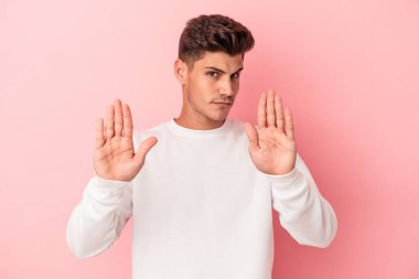 Pembe arka planda izole edilmiş genç beyaz adam elini uzatmış, dur işareti göstererek seni engelliyor..